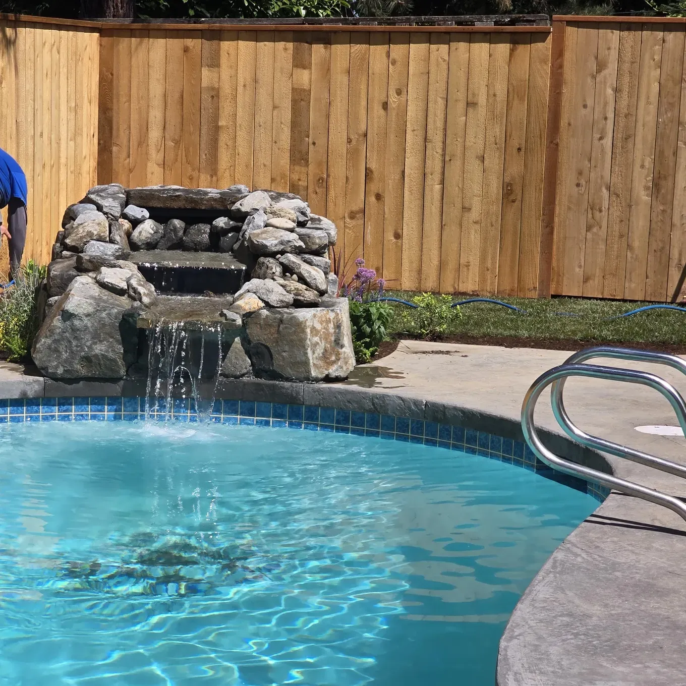 DWV Construction — backyard pool with stone waterfall and cedar privacy fence